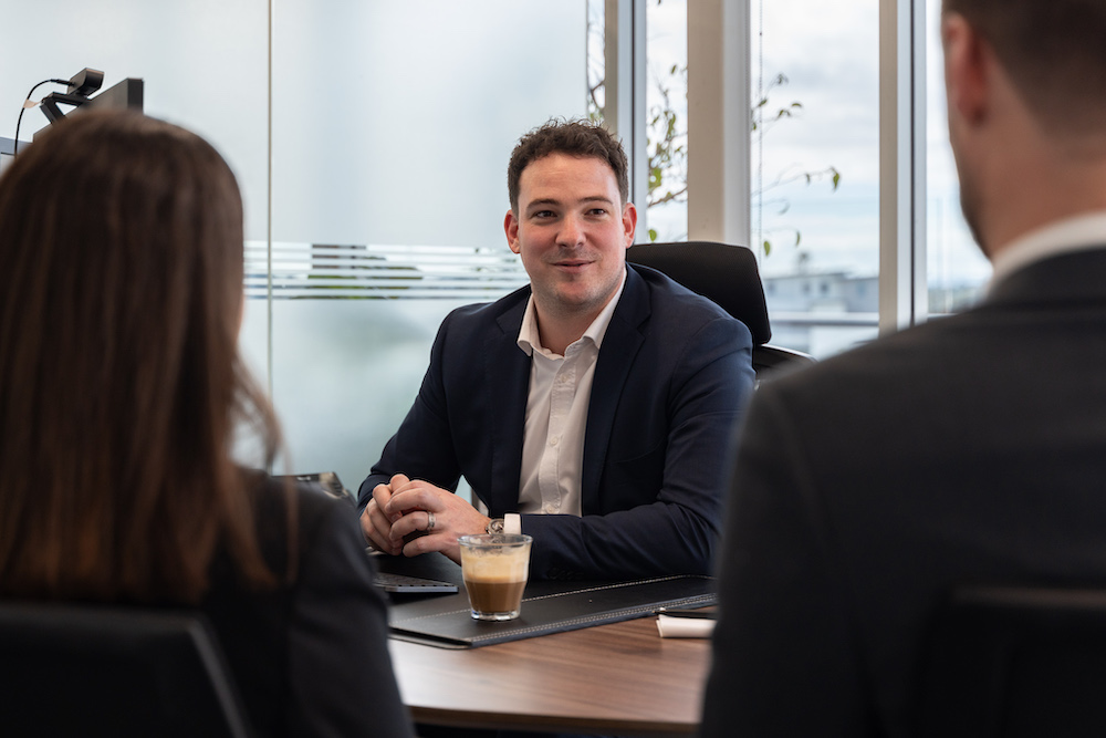 Business advisor, accountant, and BAS agent, Mace Turco, talking to two clients at his desk