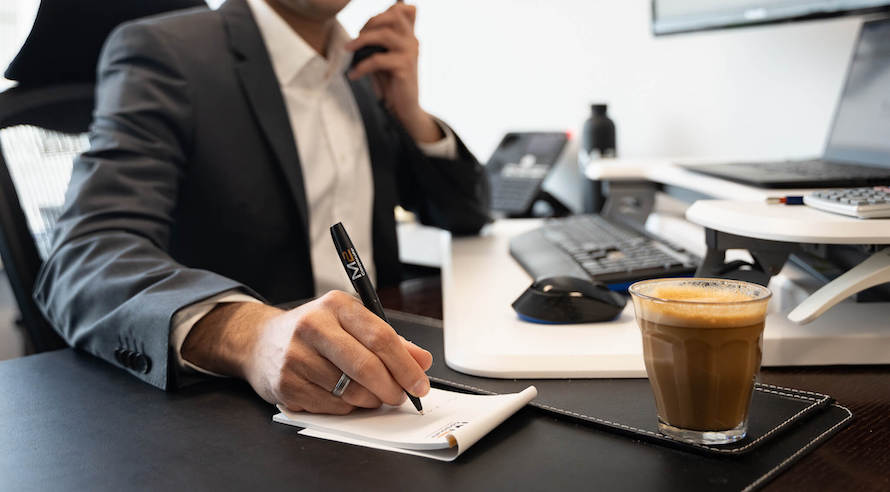 Qualified BAS agent writing a note while holding a phone